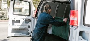 A mover loading a piece of furniture into a moving van, as loading is part of their moving services