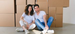 Two people sitting on the floor in front of boxes brought inside by Southlake movers.