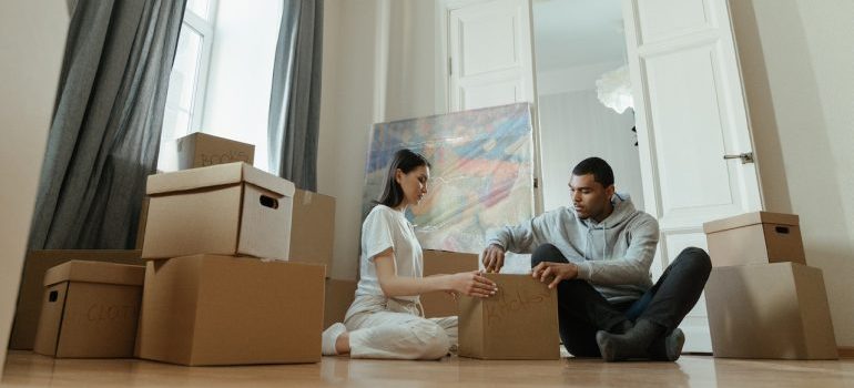 a couple moving, sitting on the floor with boxes