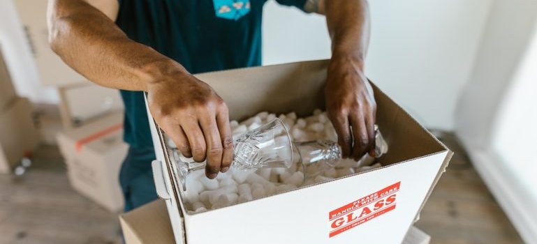 One of Frisco movers packing fragile glassware in a box.